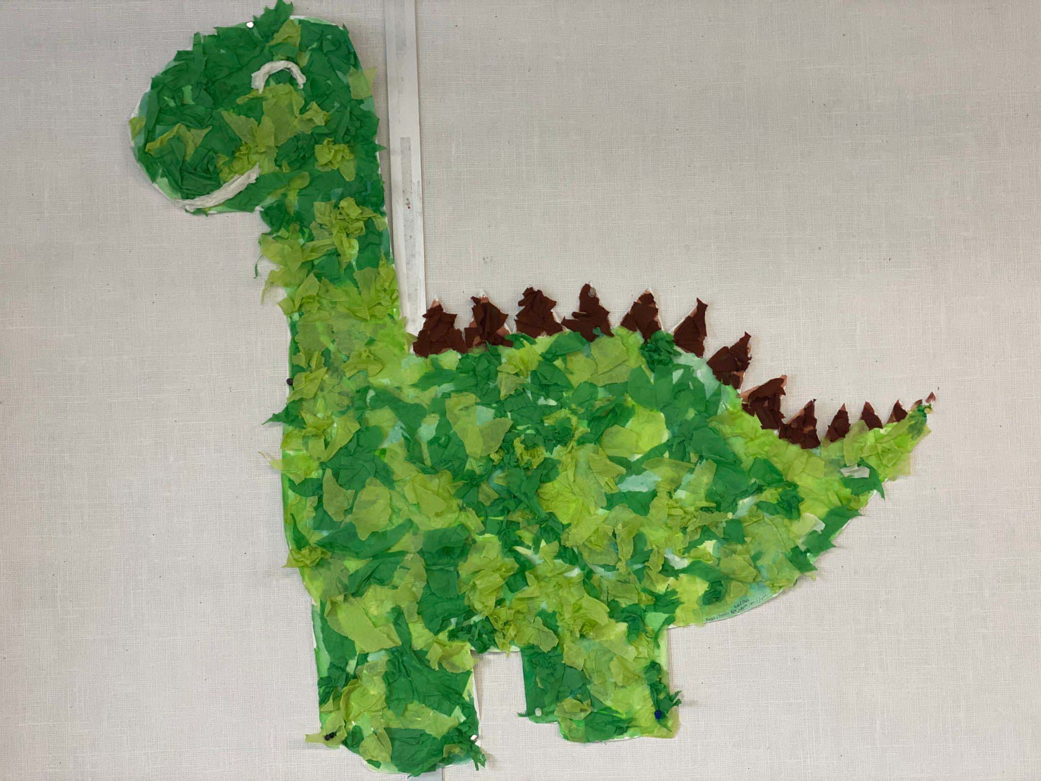 aus Papierschnipseln gebastelter grüner Dinosaurier in der Kinderkrippe Stärnschnuppe