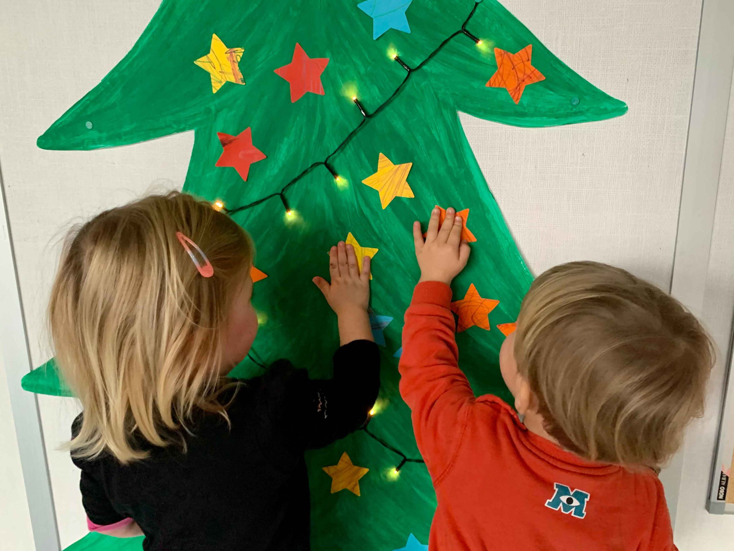 Kinder dekorieren den gemalten Christbaum in der Kinderkrippe Stärnschnuppe
